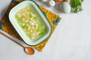 a bowl of cabbage and egg soup in white background 