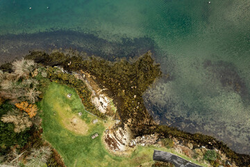 Fototapeta na wymiar Aerial top down view on a small picnic area by the ocean. Wooden tables and seat. Blue color water. Roundstone, county Galway, Ireland