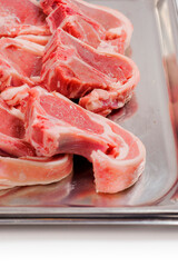 Stack of fresh lamb loin chops. Close up. Meat industry. The product is on a metal tray, Butcher craft.