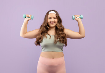 Happy pretty young european plus size female in uniform doing hand exercises with dumbbells