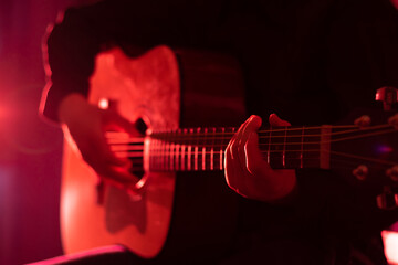 Hands of a musician playing an acoustic guitar with metal strings. Hobby. Musical instruments....