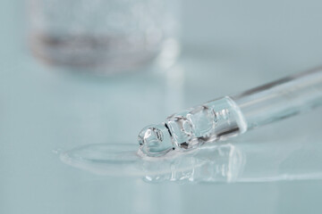 Pipette with fluid hyaluronic acid on blue background. Cosmetics and healthcare concept closeup. Dose of serum, retinol with air bubbles. Flat lay. Luxury beauty product presentation, macro