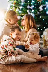 Fototapeta premium a happy family with two small children at home by the Christmas tree.