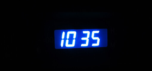 Electronic clock shows 10:35, on a black background