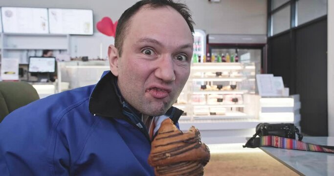 hungry man in a cafe greedily eats a croissant