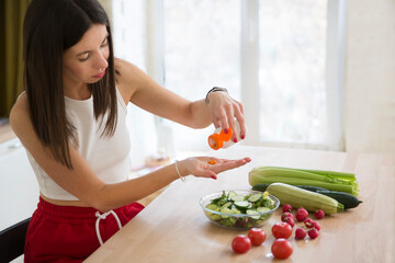 healthy lifestyle. Supporting immune system. woman takes vitamins. vitamin supplements for beauty, skin, hair, with green vegan food. at lunch at home