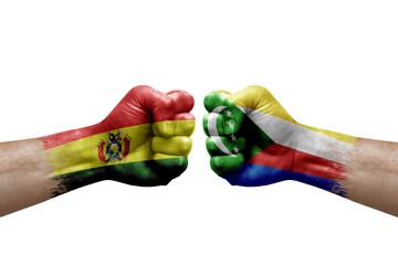 Two hands punch to each others on white background. Country flags painted fists, conflict crisis concept between bolivia and comoros