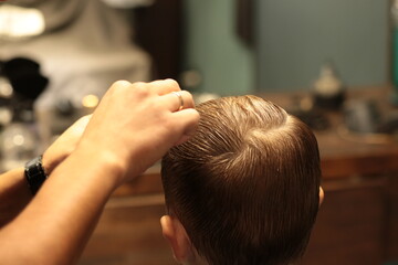 Naklejka premium Barber shop. Man in barber's chair, hairdresser styling his hair
