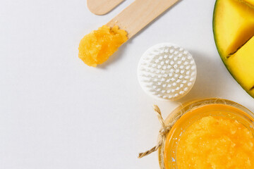Scrub with mango on a white background top view. Brush for skin cleansing and peeling at home.