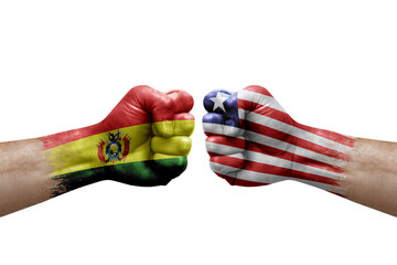 Two hands punch to each others on white background. Country flags painted fists, conflict crisis concept between bolivia and liberia