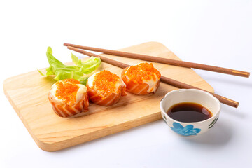 Salmon sushi roll with mayonnaise and shrimp And chopsticks are placed on a wooden chopping board. There is a cup of sauce on the side. on white background.