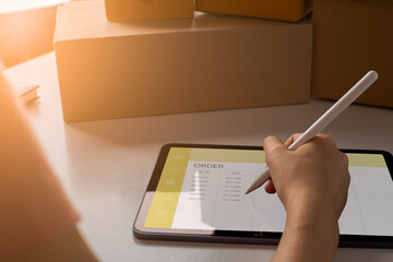 Fototapeta na wymiar Entrepreneur owner using tablet taking receive and checking online purchase shopping order, Selling online concept.