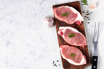 A pieces of raw fresh pork with salt on a cutting board on light background. Meat with spices