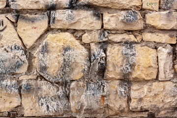 Wall made of old stones and blocks of different sizes on cement mortar. Horizontal photo.