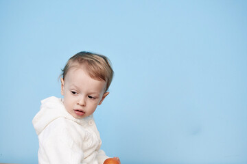 a little boy of 2 years sits in a white jacket on a blue background and thinks laughs happy sad sadness cheerful advertisement for children