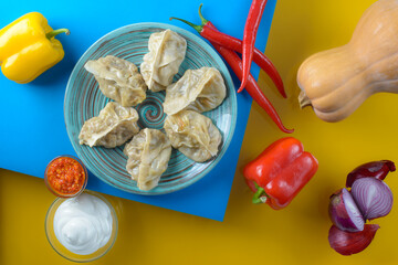 top view of delicious dumplings on plate on blue and yellow background