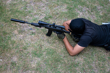 High angle view of man with weapon seen laying on grass