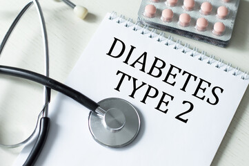 DIABETES TYPE 2 text on a notebook on a table next to a stethoscope and tablets