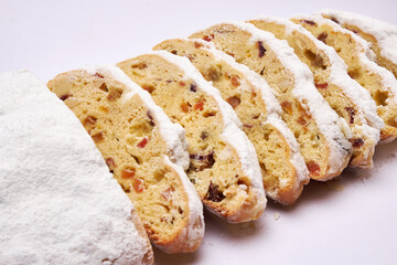 Sliced Traditional Christmas stollen cake with marzipan and dried fruit isolated on white background