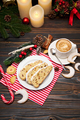 Sliced Traditional Christmas stollen cake with marzipan and New Year decorations on wooden background