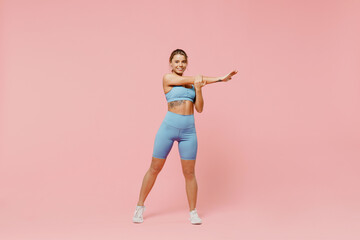 Fototapeta na wymiar Full sizeyoung sporty fitness trainer instructor woman wear blue tracksuit spend time in home gym train do stretch lunge exercise rise hands up isolated on plain pink background Workout sport concept
