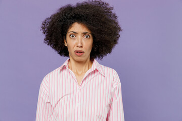 Fototapeta na wymiar Young shocked scared frightened disappointed dissatisfied woman of African American ethnicity 20s wear pink striped shirt look camera isolated on plain pastel light purple background studio portrait.