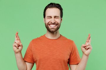 Young caucasian man 20s wear casual orange t-shirt waiting for special moment, keeping fingers...