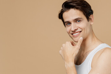 Attractive smiling happy young man 20s perfect skin in undershirt look camera prop up chin isolated...