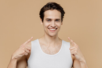 Attractive smiling fun young man 20s perfect skin in undershirt point index fingers on face smile...