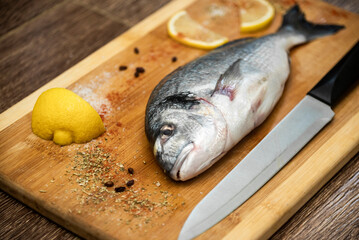 Trout carcass lying on a cutting board with cut lemon pepper and salt
