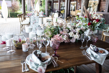 banquet table is decorated with plates, cutlery, glasses, candles and flower arrangements