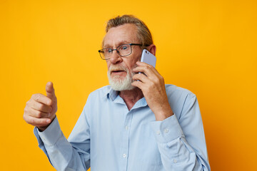 Senior grey-haired man gray beard with glasses talking on the phone isolated background