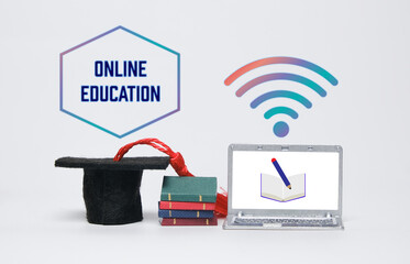 A picture of online education concept using miniature mortarboard, books, laptop and wifi symbol.