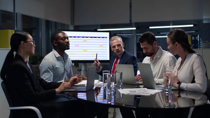 Mature executive present report on screen for business team