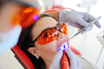 Young beautiful girl in dental glasses on examination at the dentist. Dental health, enamel, whitening, tooth filling.