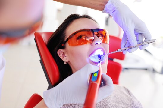 Young beautiful girl in dental glasses on examination at the dentist. Dental health, enamel, whitening, tooth filling.