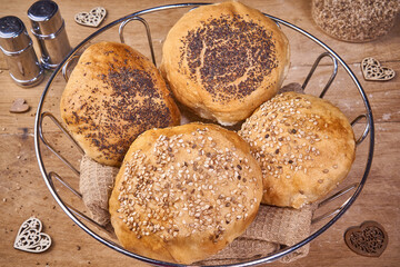 Frühstücksbrötchen mit Mohn und Sesam im Korb auf Holzbrett