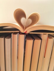Diverse books with one open book and curled leaves in the shape of a heart. Education and learning, reading