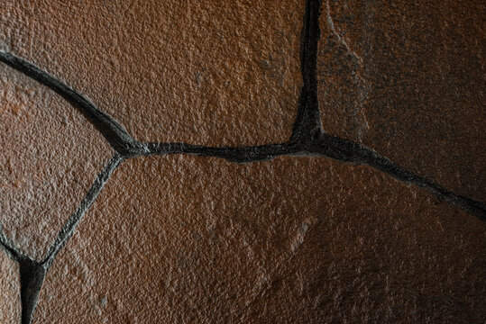 Photo of a texture that is made from a stone wall, dark brown with a red cast