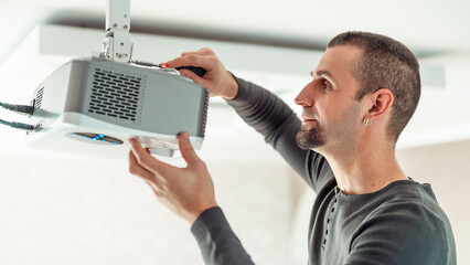 A man independently installs a multimedia video projector for a home theater or presentations on...