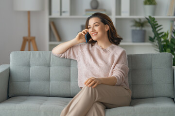 woman is using a phone sitting on a sofa