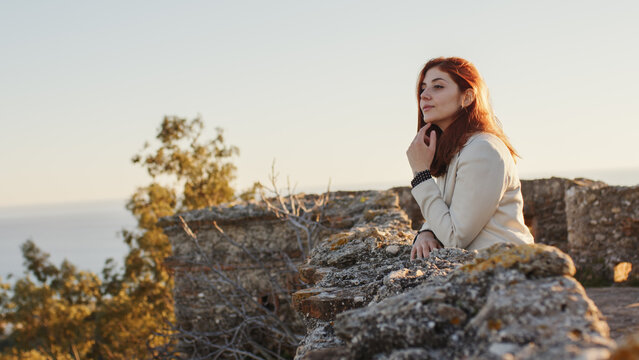 Beautiful girl with white dress explores an ancient Italian castle at sunset