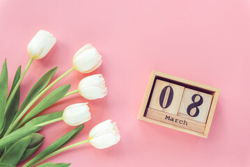 White tulips and wooden block calendar with 8 march date on pink background. Womens day concept. Top view, flat lay