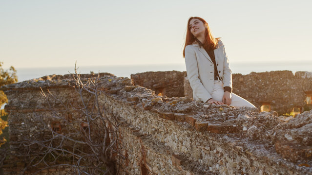 Beautiful girl with white dress explores an ancient Italian castle at sunset