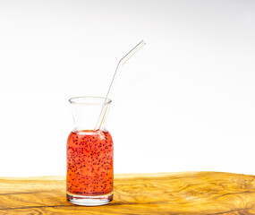 Watermelon juice with basil seeds in glass cup with straw on wooden table and white background