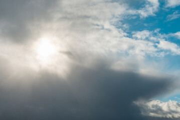 Dramatic sun illuminate through the clouds and shining on spring blue sky.