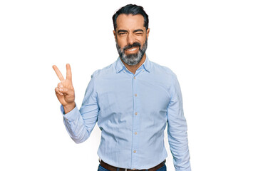 Middle aged man with beard wearing business shirt smiling with happy face winking at the camera...