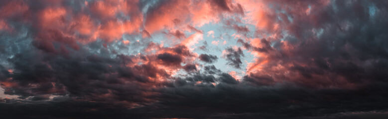 Dramatic dark sunset. Panorama of dark rain clouds in the evening. A rich red sky before a night thunderstorm