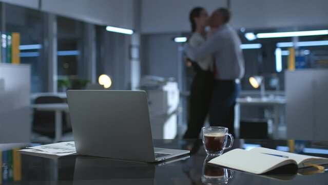 Blurred shot of colleagues hugging and making out late in empty office