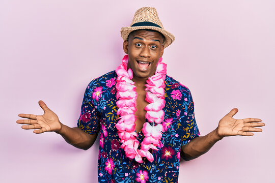 Fototapeta Young black man wearing summer shirt and hawaiian lei celebrating victory with happy smile and winner expression with raised hands